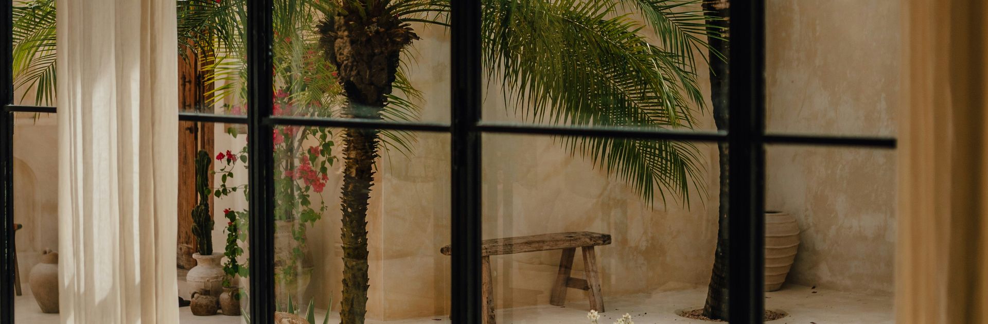 A sunlit courtyard seen through the window of a design-led property